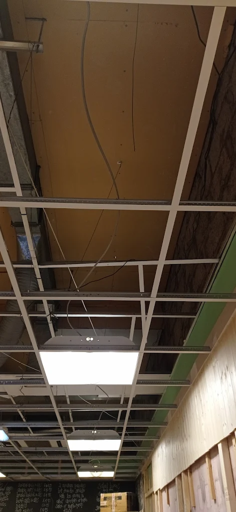 New suspended ceiling grid being installed with LED panel lighting.