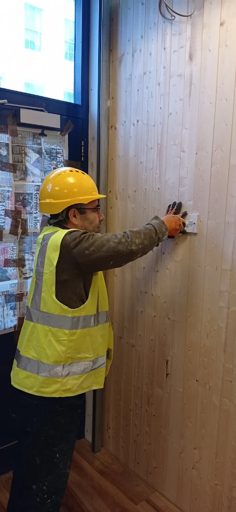 Handyman drilling timber cladding to the wall using a cordless drill.